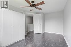 Unfurnished bedroom featuring a ceiling fan, baseboards, a closet, and dark tile patterned flooring -