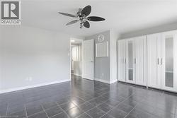 Unfurnished bedroom with ceiling fan, baseboards, and dark tile patterned flooring -