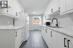 Kitchen featuring white cabinets, sink, light stone countertops, and extractor fan -