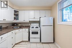 Kitchen featuring white appliances, white cabinets, glass insert cabinets, and under cabinet range hood -