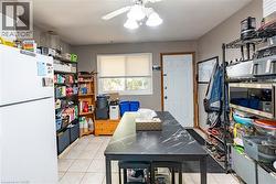 Kitchen with freestanding refrigerator, light tile patterned floors, and ceiling fan -