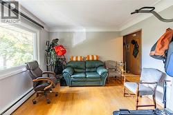 Living room with baseboard heating, wood-type flooring, healthy amount of natural light, and crown molding -