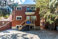 Back of house featuring a balcony, a patio, and brick siding -