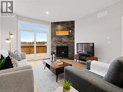 Living room with a large fireplace, recessed lighting, wood finished floors, and visible vents -