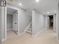 Corridor with recessed lighting, baseboards, light colored carpet, and stairway -