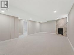 Finished below grade area with visible vents, a fireplace, baseboards, recessed lighting, and light colored carpet -