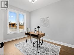 Office area with baseboards, visible vents, and wood finished floors -