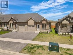 View of front of house featuring driveway, a front lawn, an attached garage, stone siding, and stucco siding -