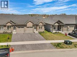 View of front of home with an attached garage, a front lawn, driveway, and stone siding -