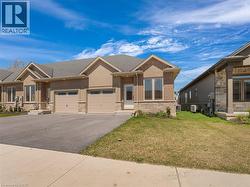 View of front of home featuring an attached garage, brick siding, stone siding, a front yard, and driveway -