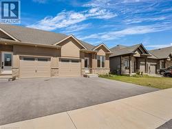 View of front of property with driveway, roof with shingles, an attached garage, stone siding, and stucco siding -