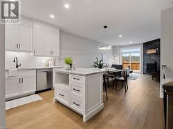 Kitchen featuring dishwasher, a center island, white cabinetry, open floor plan, and light wood-type flooring -