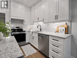 Kitchen featuring a sink, tasteful backsplash, stainless steel appliances, and white cabinetry -