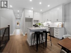 Kitchen with white cabinets, appliances with stainless steel finishes, a sink, and a center island -