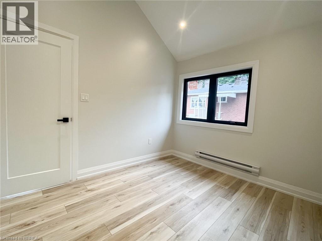 Spare room featuring a baseboard radiator, light wood-style flooring, and lofted ceiling - 110 Deschene Avenue, Hamilton, ON - Indoor Photo Showing Other Room