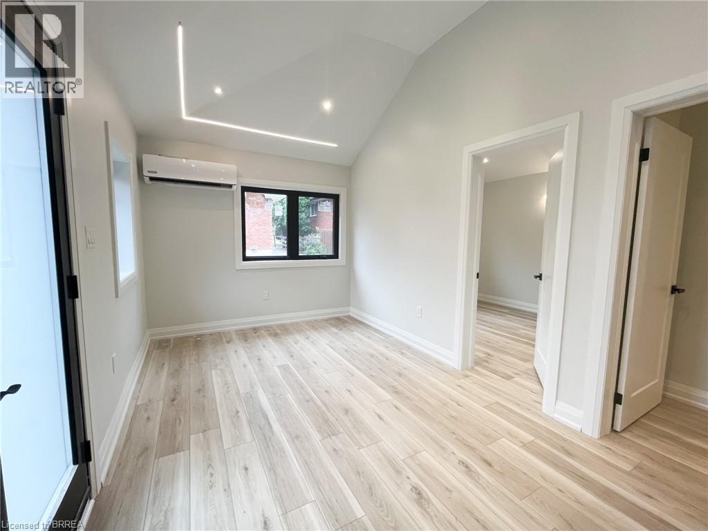 Unfurnished living room with light wood-style flooring, a wall unit AC, high vaulted ceiling, and recessed lighting - 110 Deschene Avenue, Hamilton, ON - Indoor Photo Showing Other Room