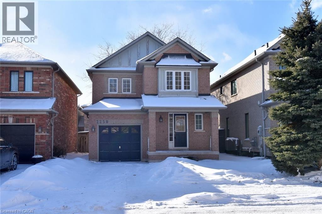 View of front of home with a garage, brick siding, board and batten siding, and covered porch - 2258 Empire Crescent, Burlington, ON - Outdoor With Facade