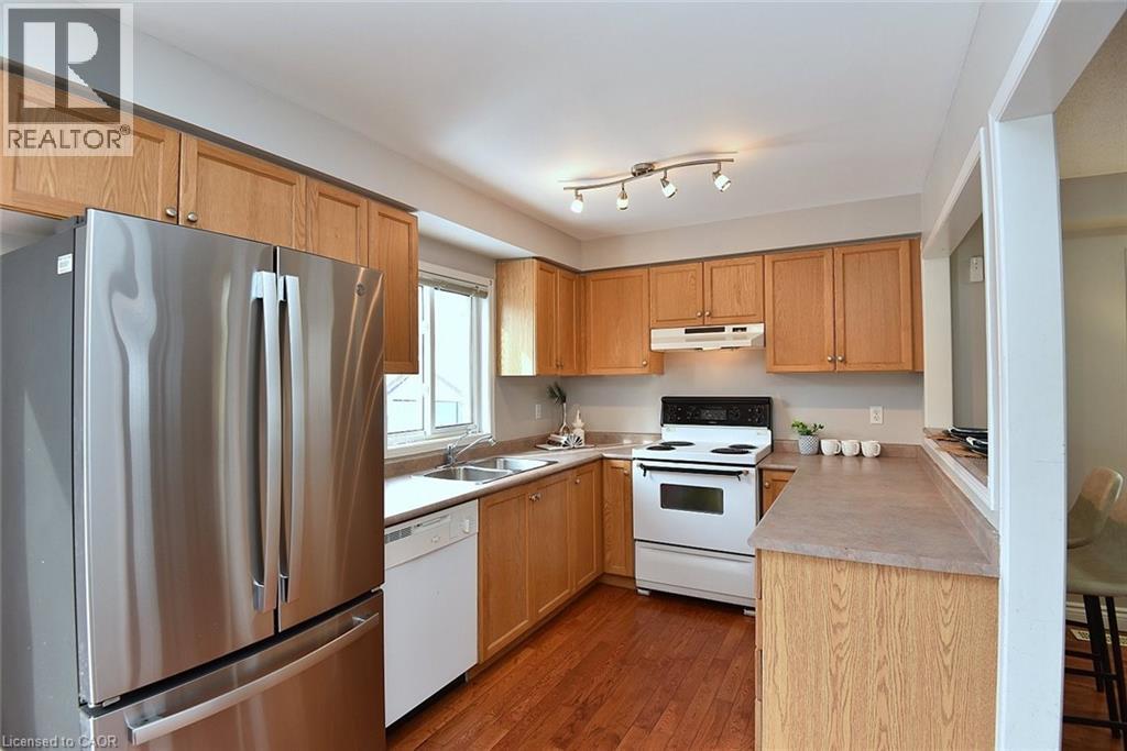 Kitchen with white appliances, light countertops, dark wood finished floors, and under cabinet range hood - 2258 Empire Crescent, Burlington, ON - Indoor Photo Showing Kitchen With Double Sink