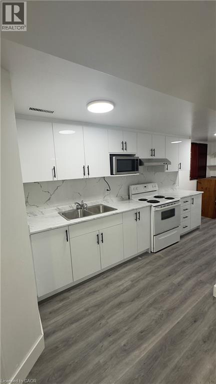 Kitchen with white cabinetry, white electric stove, and light wood-type flooring - 18 Ingleside Drive, Kitchener, ON - Indoor Photo Showing Kitchen With Double Sink