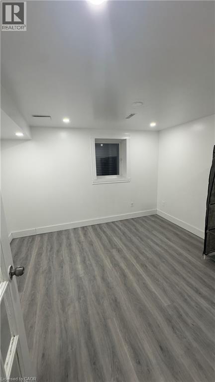 Finished basement with dark wood-style flooring and recessed lighting - 18 Ingleside Drive, Kitchener, ON - Indoor
