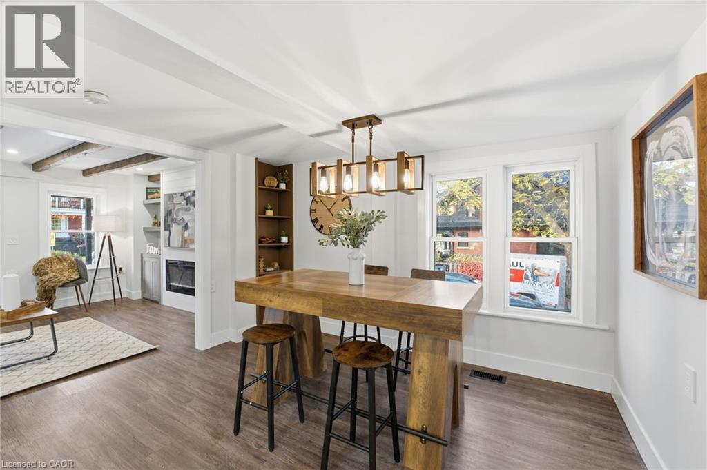 Dining area with beamed ceiling, wood finished floors, a glass covered fireplace, and a chandelier - 4255 William Street, Beamsville, ON - Indoor Photo Showing Dining Room