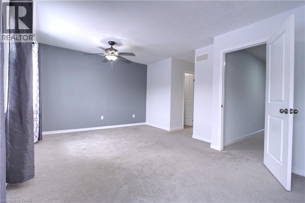 Unfurnished room with light colored carpet, a textured ceiling, and a ceiling fan - 919 Zeller Crescent, Kitchener, ON - Indoor Photo Showing Other Room