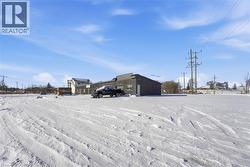 Snow covered parking with an outbuilding -