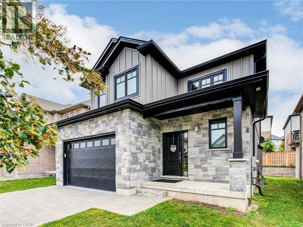 View of front of property with a porch, board and batten siding, an attached garage, decorative driveway, and stone siding - 2527 Holbrook Drive, London, ON - Outdoor