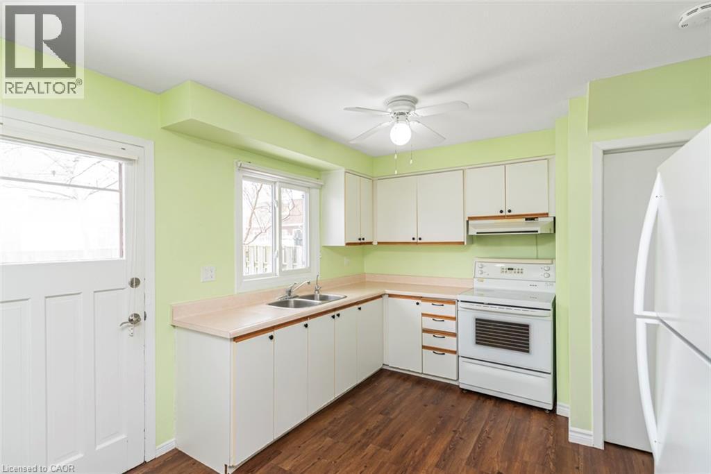 Kitchen featuring white appliances, light countertops, white cabinets, dark wood-style floors, and under cabinet range hood - 48 Riverdale Drive Unit# 2, Hamilton, ON - Indoor Photo Showing Kitchen With Double Sink