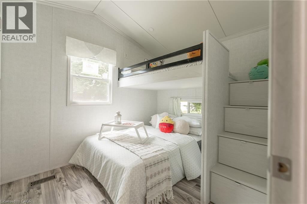 Bedroom featuring wood finished floors, multiple windows, and vaulted ceiling - 85 Hutchinson Beach Road Unit# B56, Huntsville, ON - Indoor Photo Showing Bedroom