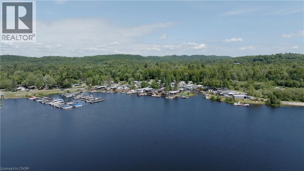 Aerial overview of property's location with a forest and a nearby body of water - 85 Hutchinson Beach Road Unit# B56, Huntsville, ON - Outdoor With Body Of Water With View