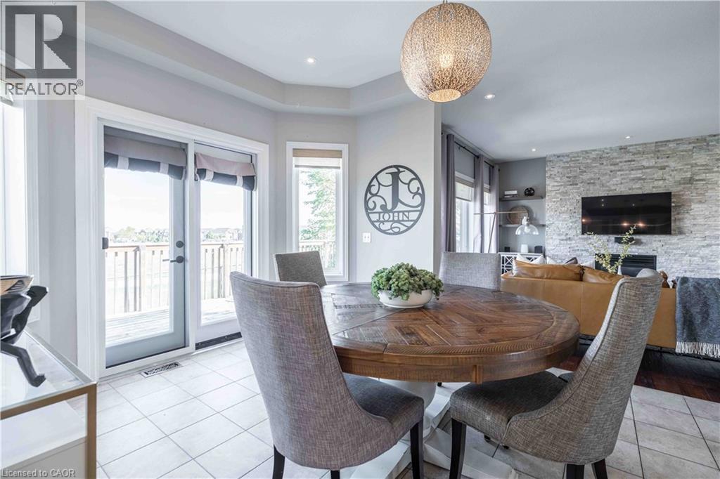 Sunlight bathes the space in warmth. Garden doors lead to elevated deck - 51 Showcase Drive, Hamilton, ON - Indoor Photo Showing Dining Room With Fireplace