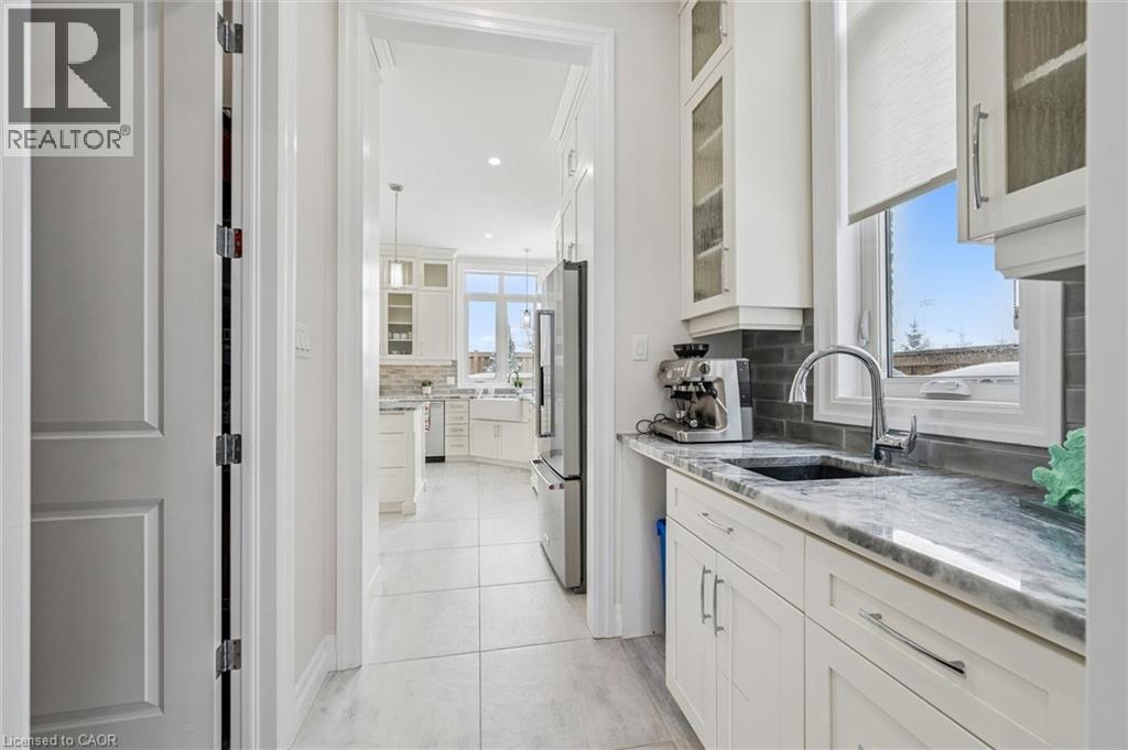 Kitchen featuring glass insert cabinets, white cabinetry, light stone countertops, recessed lighting, and high end refrigerator - 263 Chestnut Ridge, Waterloo, ON - Indoor Photo Showing Kitchen With Upgraded Kitchen