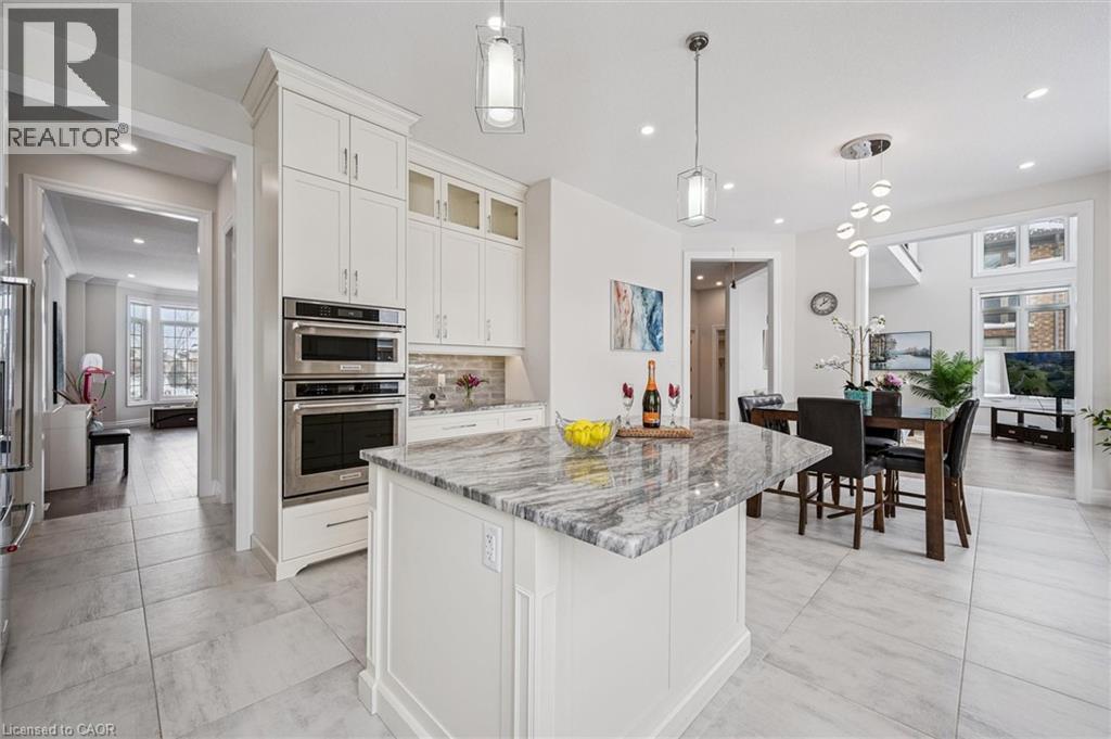 Kitchen featuring light stone counters, white cabinetry, pendant lighting, glass insert cabinets, and stainless steel appliances - 263 Chestnut Ridge, Waterloo, ON - Indoor Photo Showing Kitchen With Upgraded Kitchen