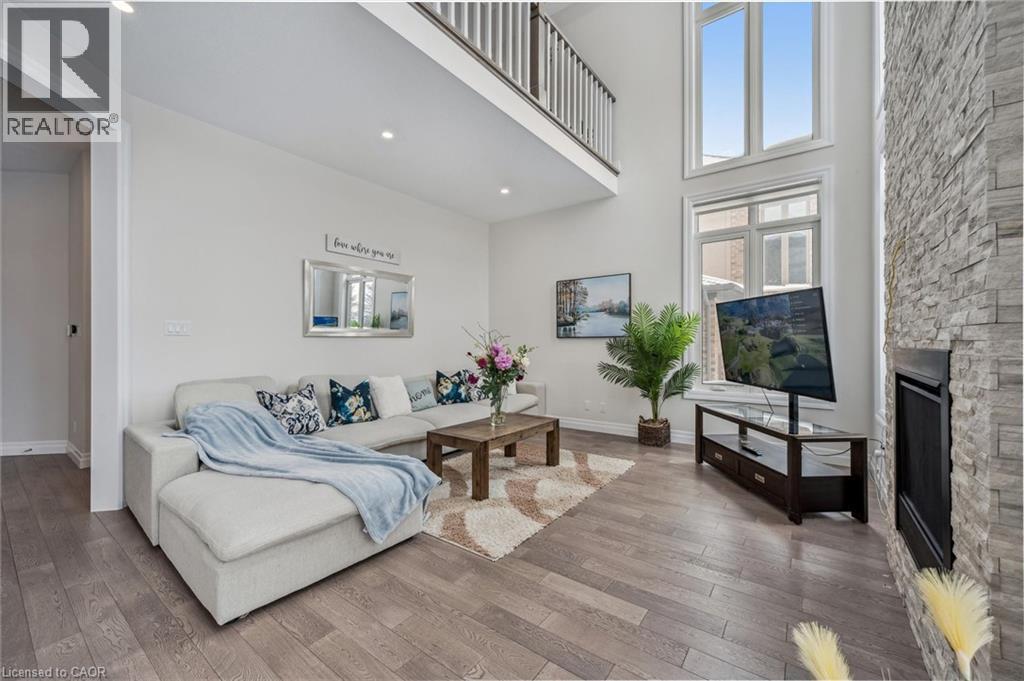 Living area featuring a stone fireplace, a towering ceiling, and wood-type flooring - 263 Chestnut Ridge, Waterloo, ON - Indoor Photo Showing Living Room With Fireplace