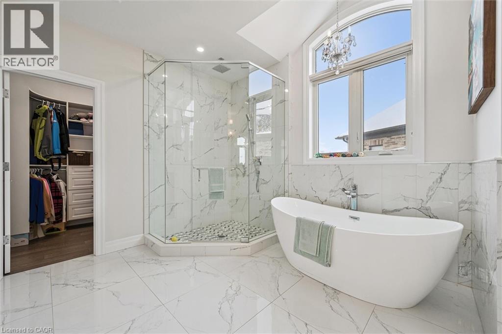 Full bath featuring light marble finish flooring, a freestanding tub, a marble finish shower, a spacious closet, and recessed lighting - 263 Chestnut Ridge, Waterloo, ON - Indoor Photo Showing Bathroom