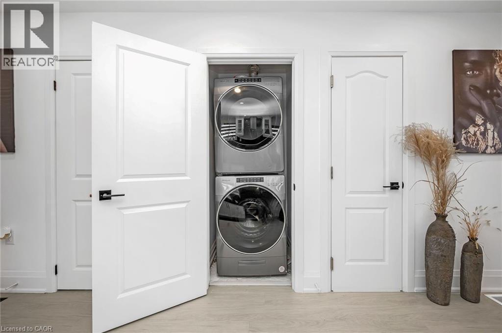 Laundry room featuring stacked washer / dryer and light wood-style flooring - 525 Britannia Avenue, Hamilton, ON - Indoor Photo Showing Laundry Room