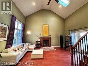 Living area featuring a skylight, a fireplace with raised hearth, a ceiling fan, wood finished floors, and stairway - 158 River Run Road, Drayton, ON - Indoor With Fireplace