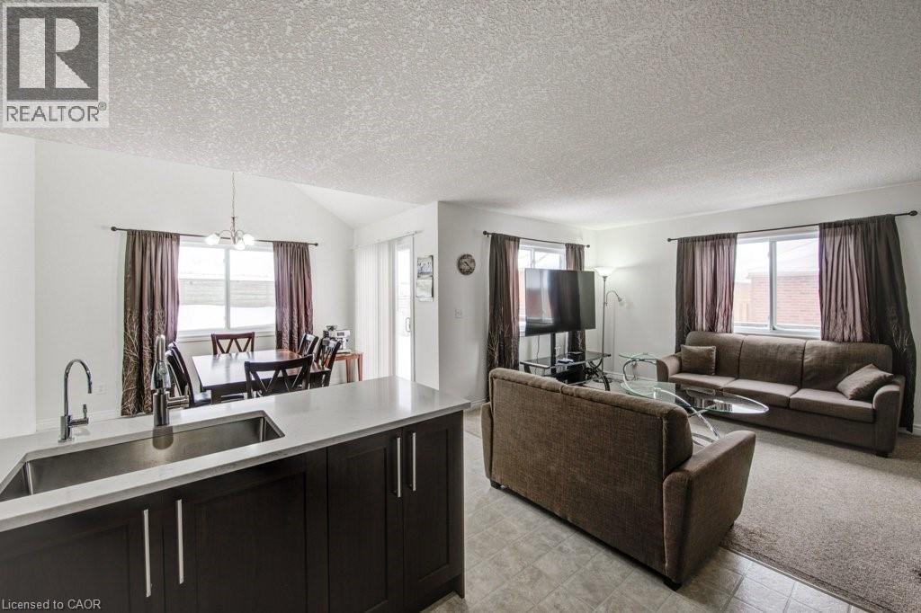 Living area featuring a textured ceiling and a chandelier - 711 Southwood Way, Woodstock, ON - Indoor Photo Showing Other Room