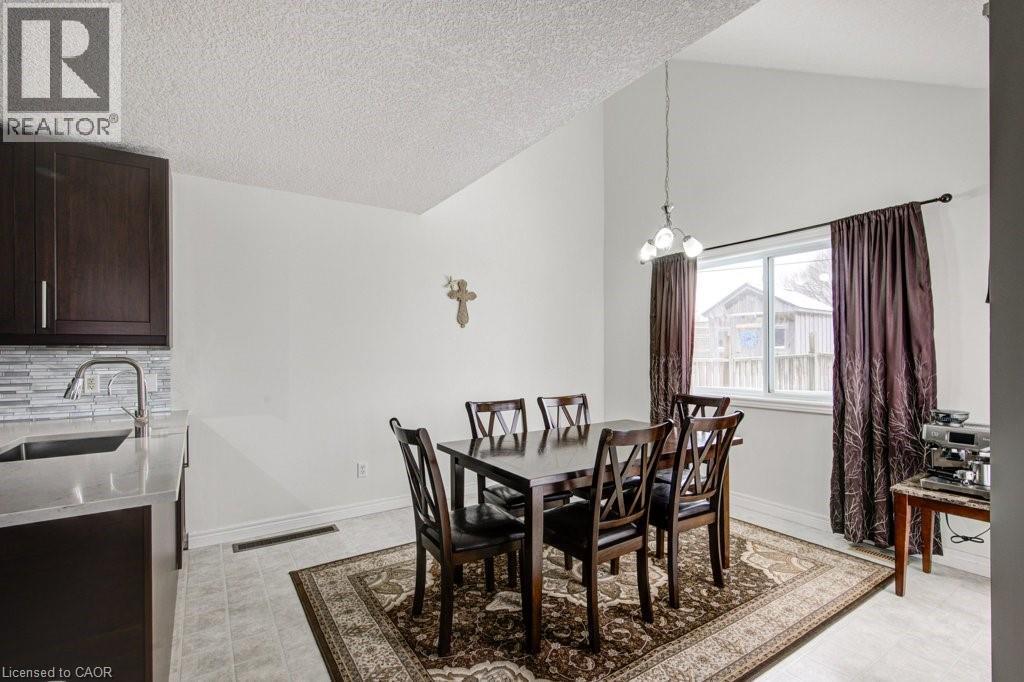 Dining space with vaulted ceiling, a chandelier, and a textured ceiling - 711 Southwood Way, Woodstock, ON - Indoor