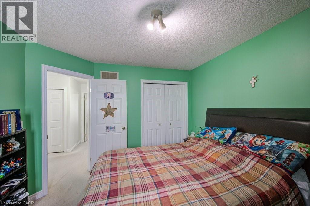 Bedroom with light carpet, a textured ceiling, and a closet - 711 Southwood Way, Woodstock, ON - Indoor Photo Showing Bedroom