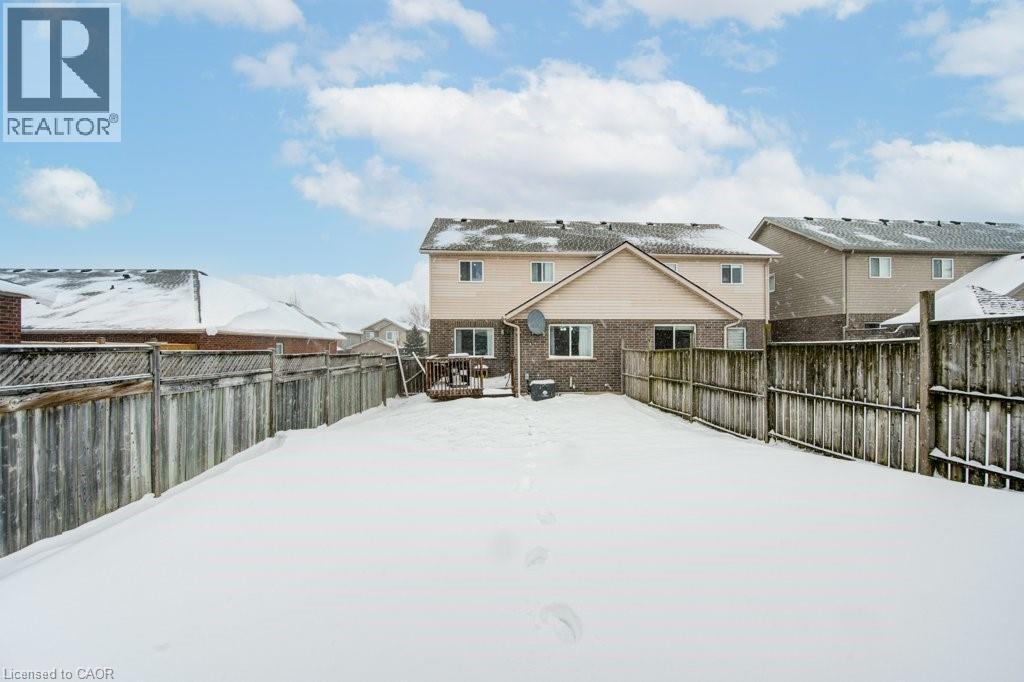Snow covered property with a fenced backyard, brick siding, and a deck - 711 Southwood Way, Woodstock, ON - Outdoor