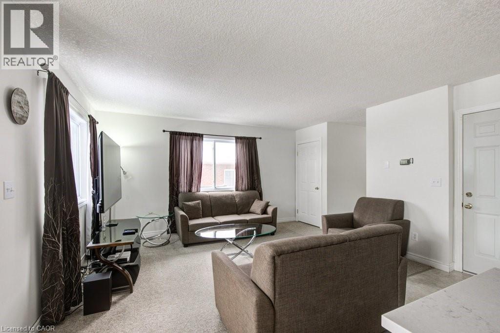 Living room featuring a textured ceiling and light colored carpet - 711 Southwood Way, Woodstock, ON - Indoor Photo Showing Living Room