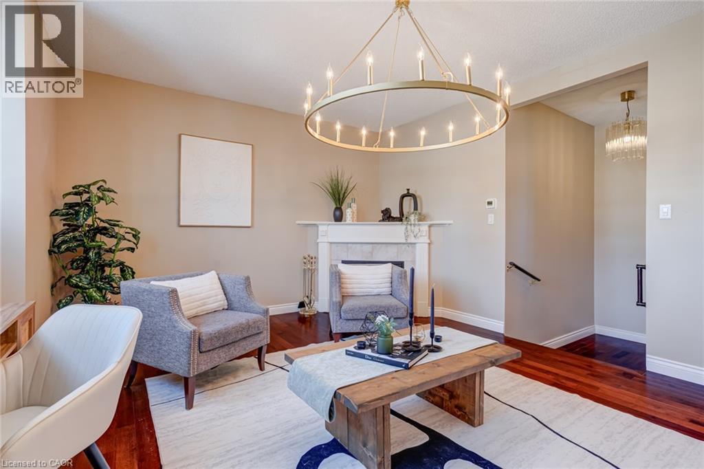 Living area featuring a tile fireplace, dark wood-style floors, and a chandelier - 15 Claudette Gate, Hamilton, ON - Indoor Photo Showing Living Room