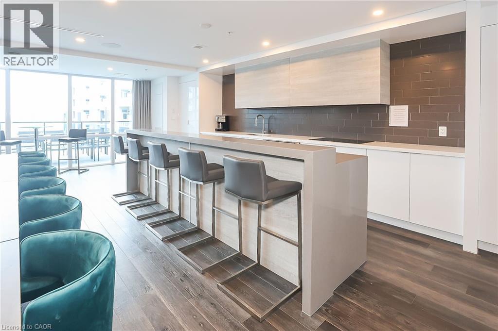 Kitchen with modern cabinets, a wall of windows, a kitchen island, a kitchen breakfast bar, and light brown cabinetry - 16 Concord Place Unit# 431, Grimsby, ON - Indoor