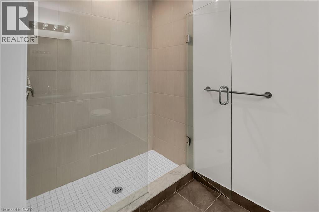 Bathroom featuring a stall shower and dark tile patterned flooring - 16 Concord Place Unit# 431, Grimsby, ON - Indoor Photo Showing Bathroom