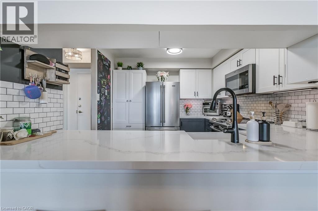 Kitchen featuring white cabinets, backsplash, appliances with stainless steel finishes, and light stone counters - 3845 Lakeshore Boulevard W Unit# 804, Etobicoke, ON - Indoor Photo Showing Kitchen With Stainless Steel Kitchen With Upgraded Kitchen