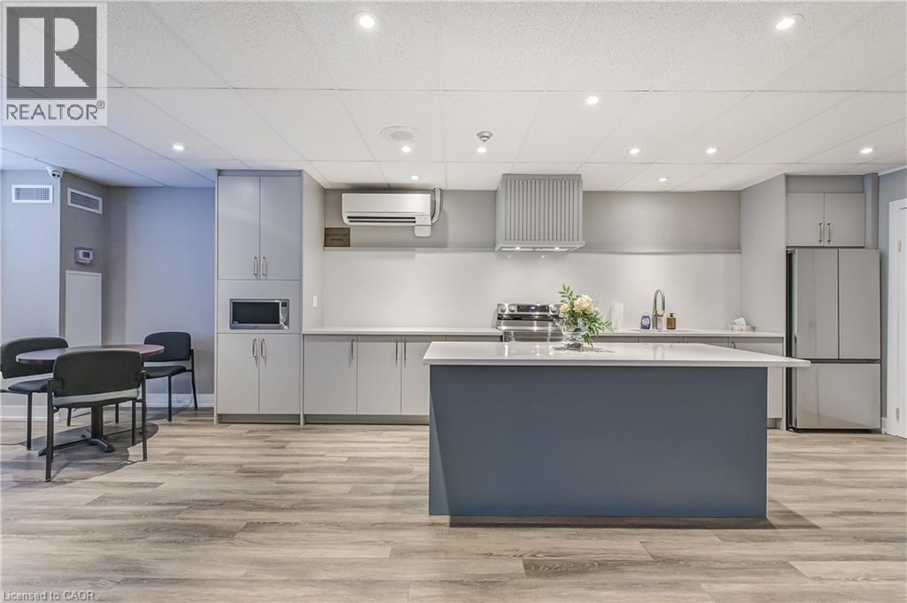 Kitchen with gray cabinetry, recessed lighting, appliances with stainless steel finishes, a kitchen island, and a wall unit AC - 3845 Lakeshore Boulevard W Unit# 804, Etobicoke, ON - Indoor Photo Showing Kitchen With Upgraded Kitchen