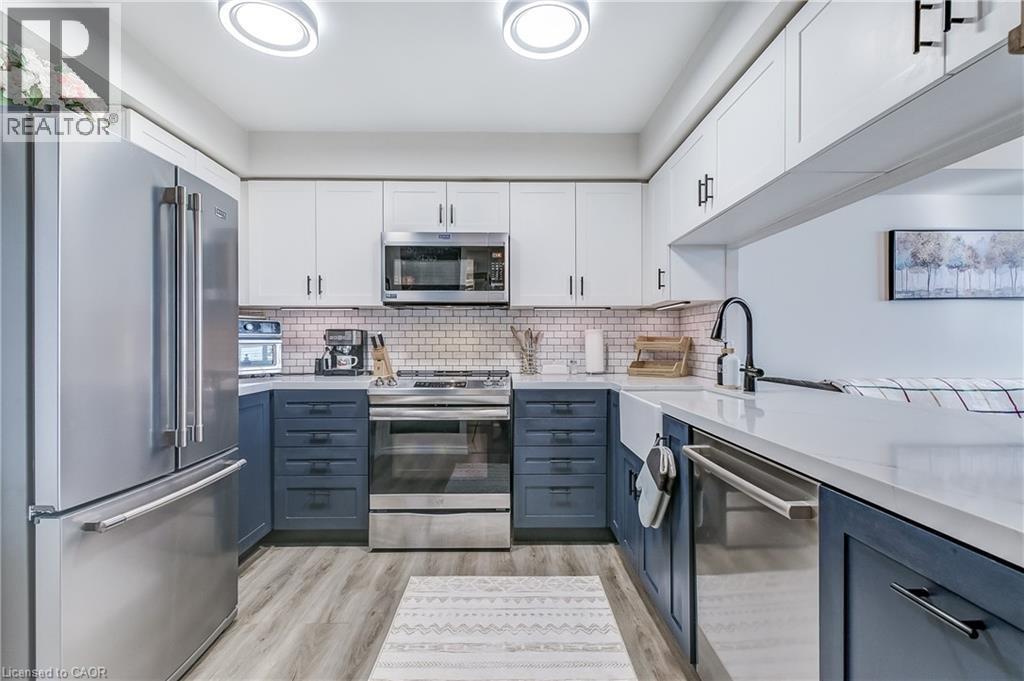 Kitchen with white cabinets, stainless steel appliances, light wood finished floors, light stone countertops, and decorative backsplash - 3845 Lakeshore Boulevard W Unit# 804, Etobicoke, ON - Indoor Photo Showing Kitchen With Stainless Steel Kitchen With Upgraded Kitchen