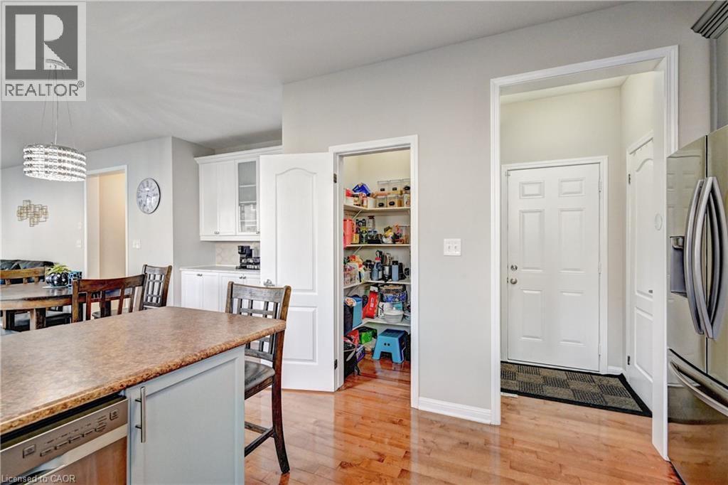 Kitchen with light wood-type flooring, appliances with stainless steel finishes, a kitchen bar, hanging light fixtures, and glass insert cabinets - 32 Weir Street, Cambridge, ON - Indoor